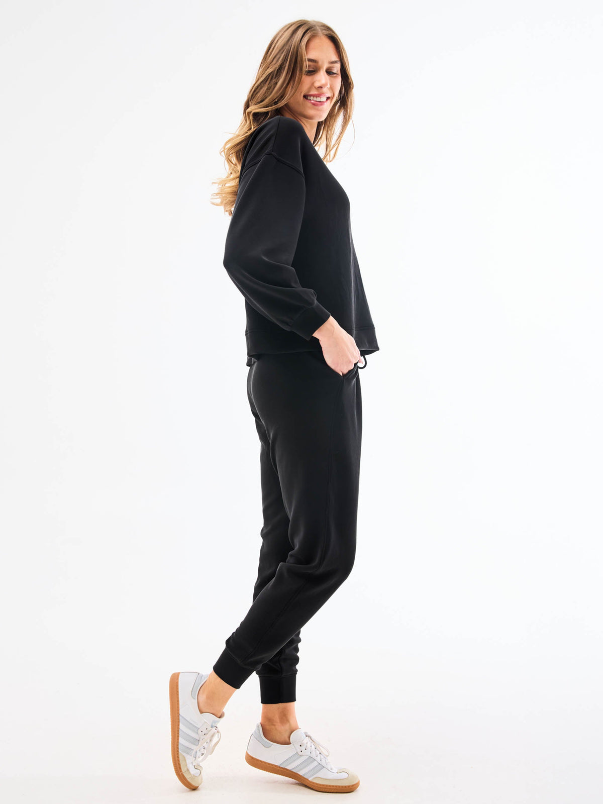 Woman wearing a black outfit with white sneakers on a white background