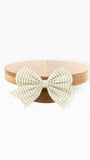 A light green and white striped bow tied around a round natural wood tray, photographed against a solid white background.