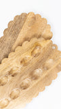 Three scalloped-edge wooden serving boards with raised oval indentations, shown overlapping on a plain white background.