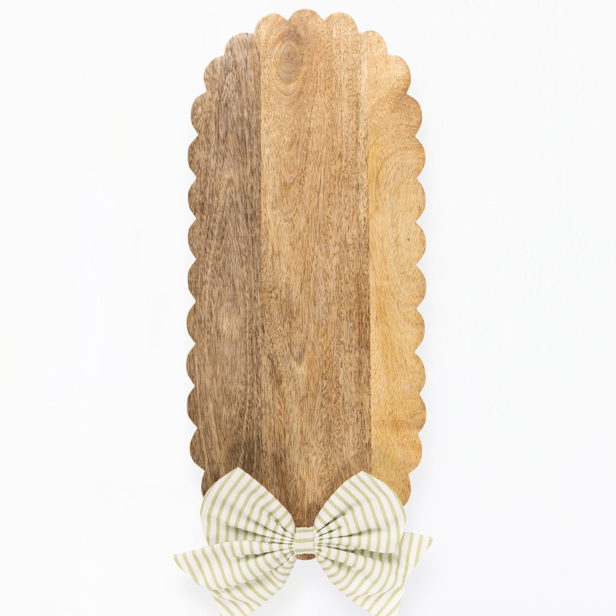 A vertical wooden serving board with a scalloped edge and a striped bow at the bottom, shown on a plain white background.