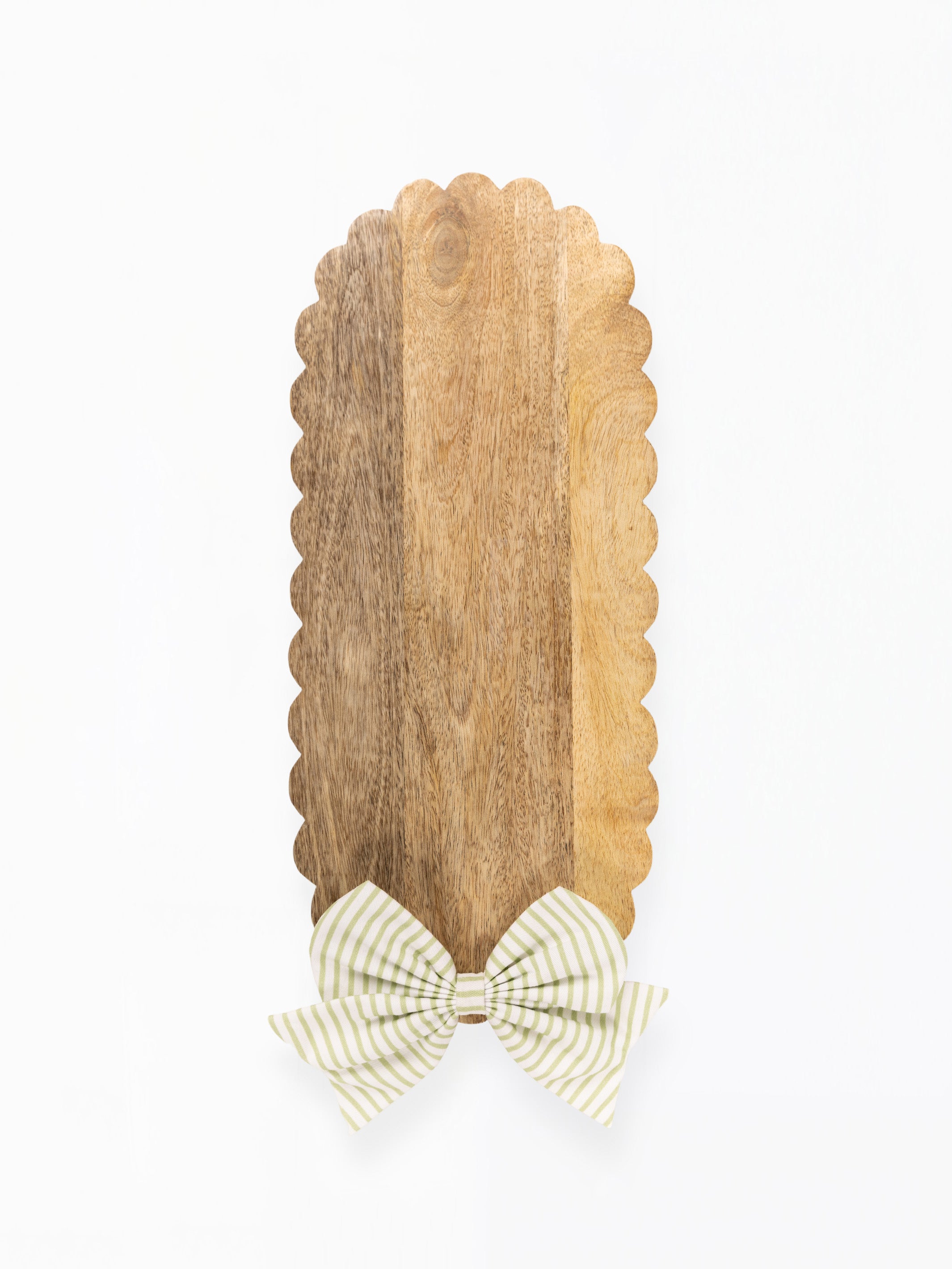 A vertical wooden serving board with a scalloped edge and a striped bow at the bottom, shown on a plain white background.
