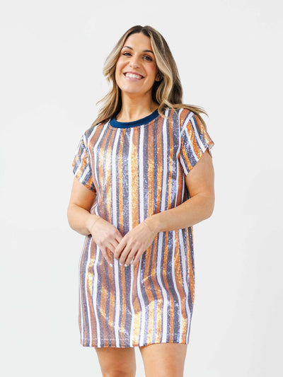 Woman wearing a striped navy and orange sequin dress on a plain background