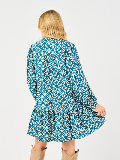 Woman wearing a blue floral dress and tan knee-high boots on a white background