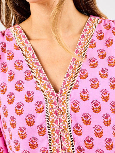 woman in floral pink, flowy blouse wearing dark blue jeans on a white background