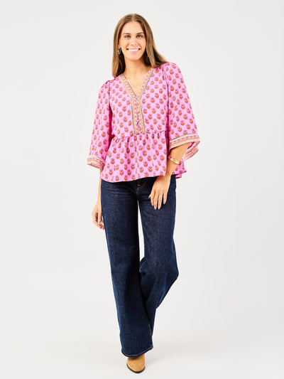 woman in floral pink, flowy blouse wearing dark blue jeans on a white background