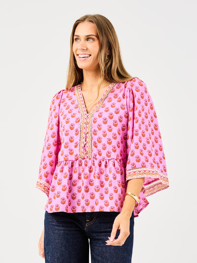 woman in floral pink, flowy blouse wearing dark blue jeans on a white background