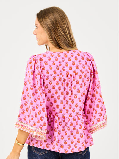 Woman wearing a pink blouse with a pattern on a plain background