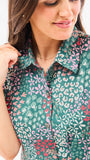 A woman standing in an elegant pose wearing a green floral dress with a classic point collar and bubble sleeves.