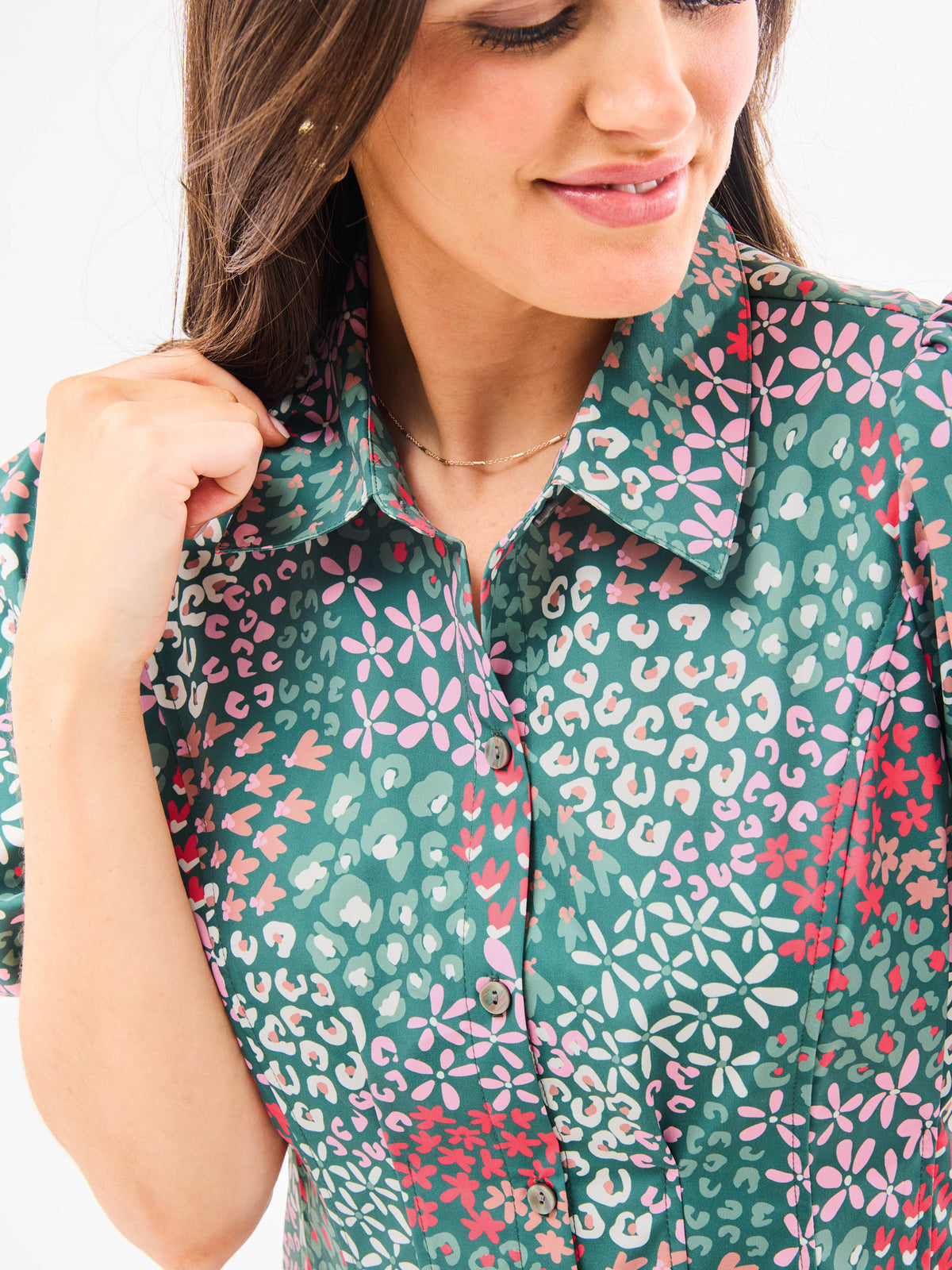 A woman standing in an elegant pose wearing a green floral dress with a classic point collar and bubble sleeves.