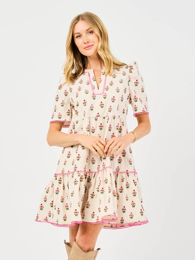 Woman wearing a floral dress featuring puff sleeves, pink trim on a white background