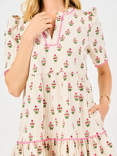 Woman wearing a floral dress featuring puff sleeves, pink trim on a white background