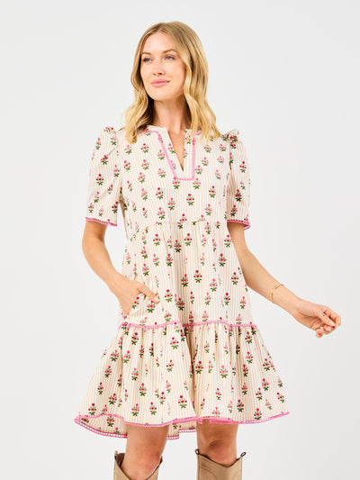 Woman wearing a floral dress featuring puff sleeves, pink trim on a white background