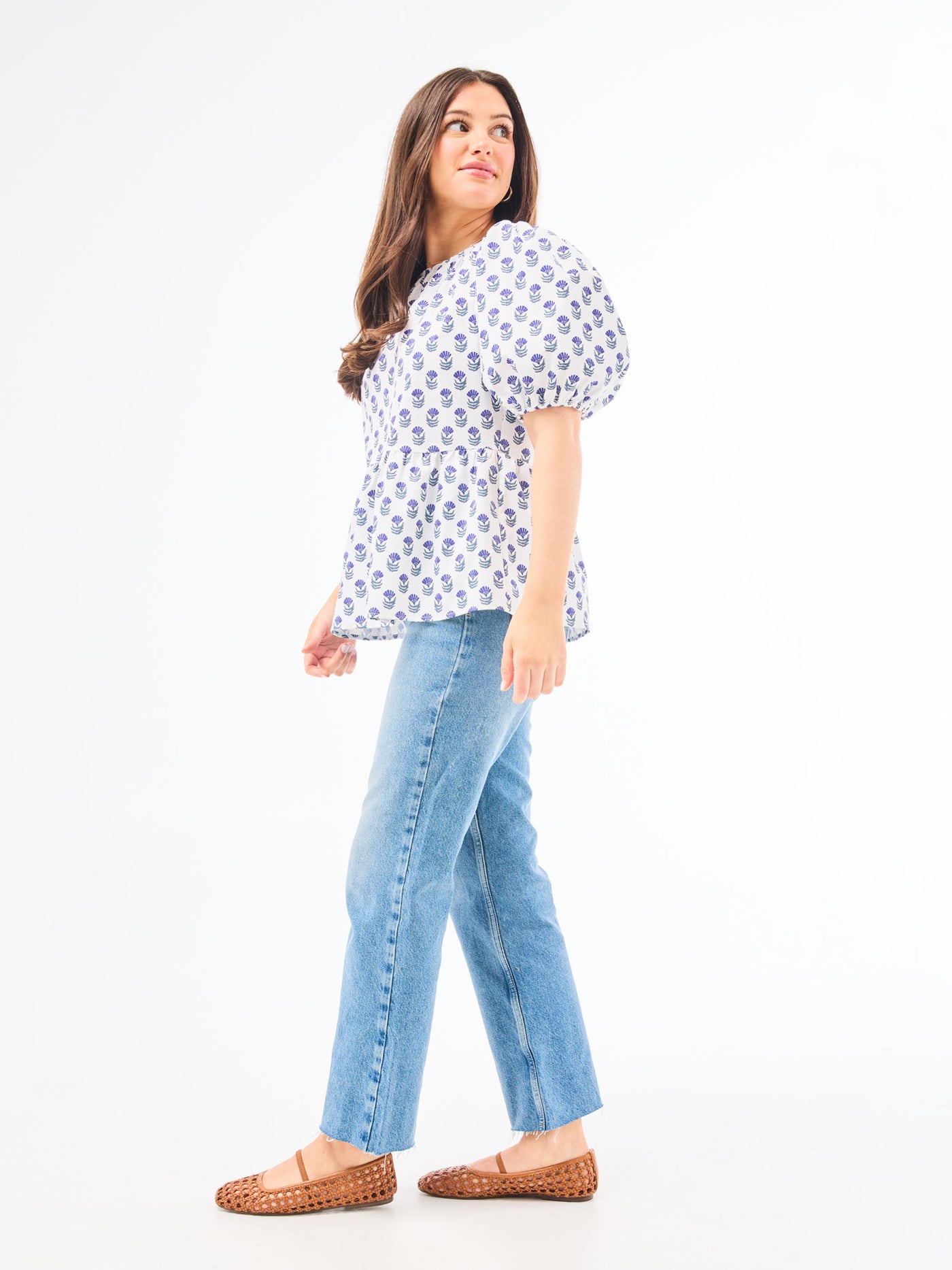 A woman wearing a floral foulard navy top with short puff sleeves and a jewel neckline.