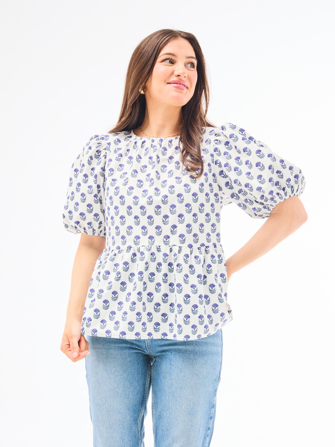 A woman wearing a floral foulard navy top with short puff sleeves and a jewel neckline.