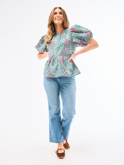 Woman wearing a floral blouse and blue jeans on a white background
