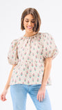 Woman wearing a floral blouse with puffed sleeves on a white background