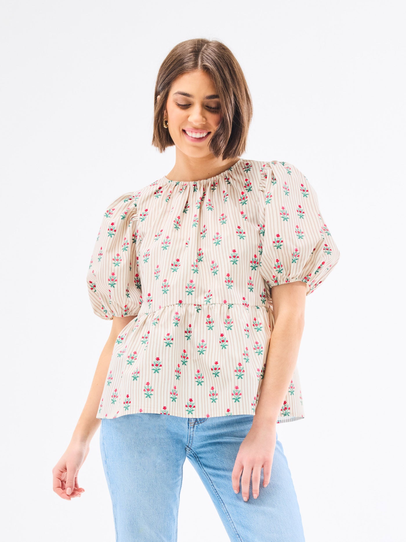 Woman wearing a floral blouse with puffed sleeves on a white background