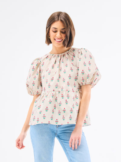 Woman wearing a floral blouse with puffed sleeves on a white background