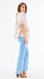 Woman wearing a floral blouse and light blue jeans on a white background