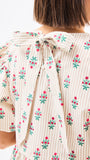 Close-up of a person wearing a floral dress with a bow detail on a white background