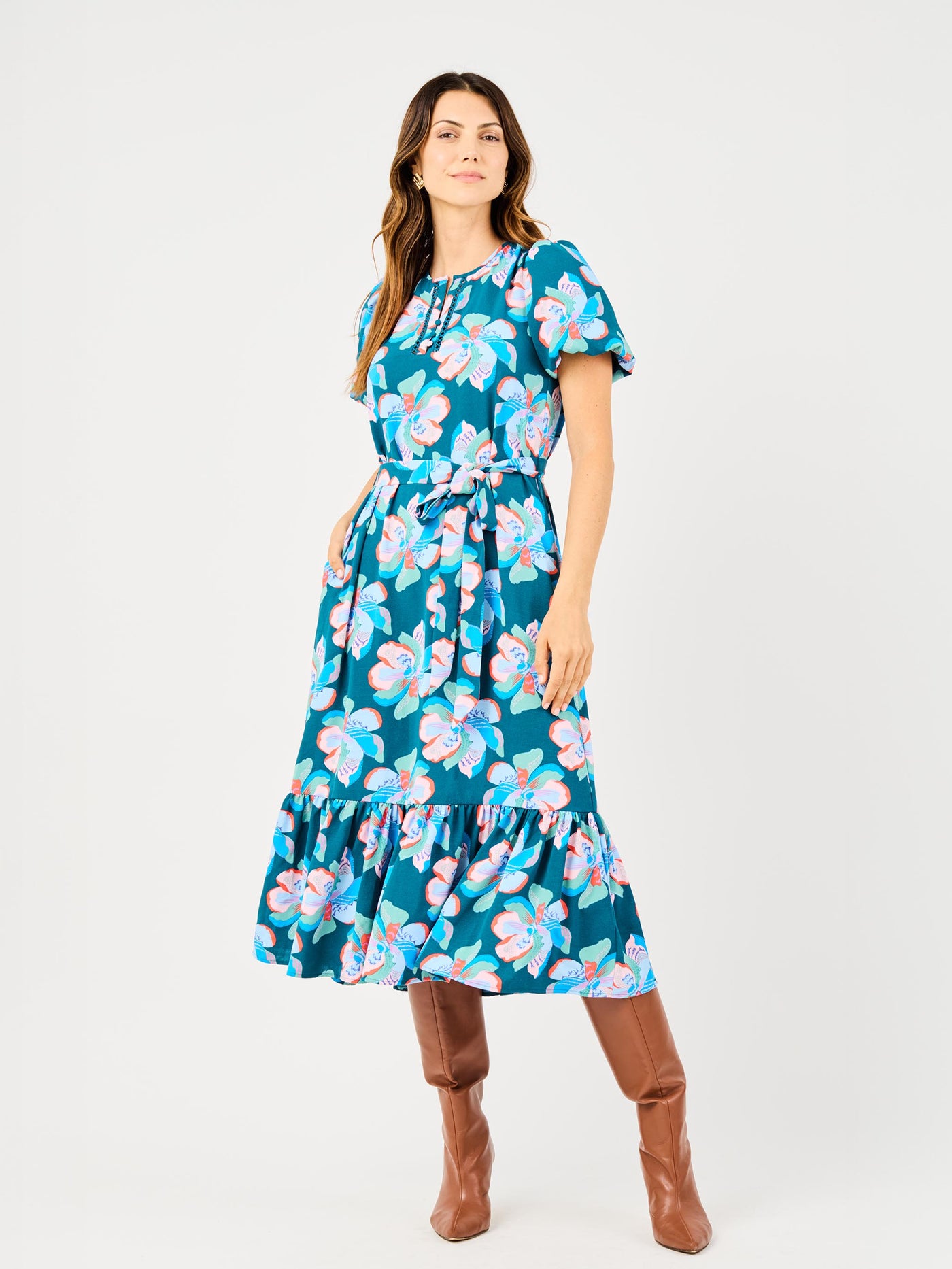 A model wearing a midi-length floral dress with short bubble sleeves and a split neckline, paired with brown boots.