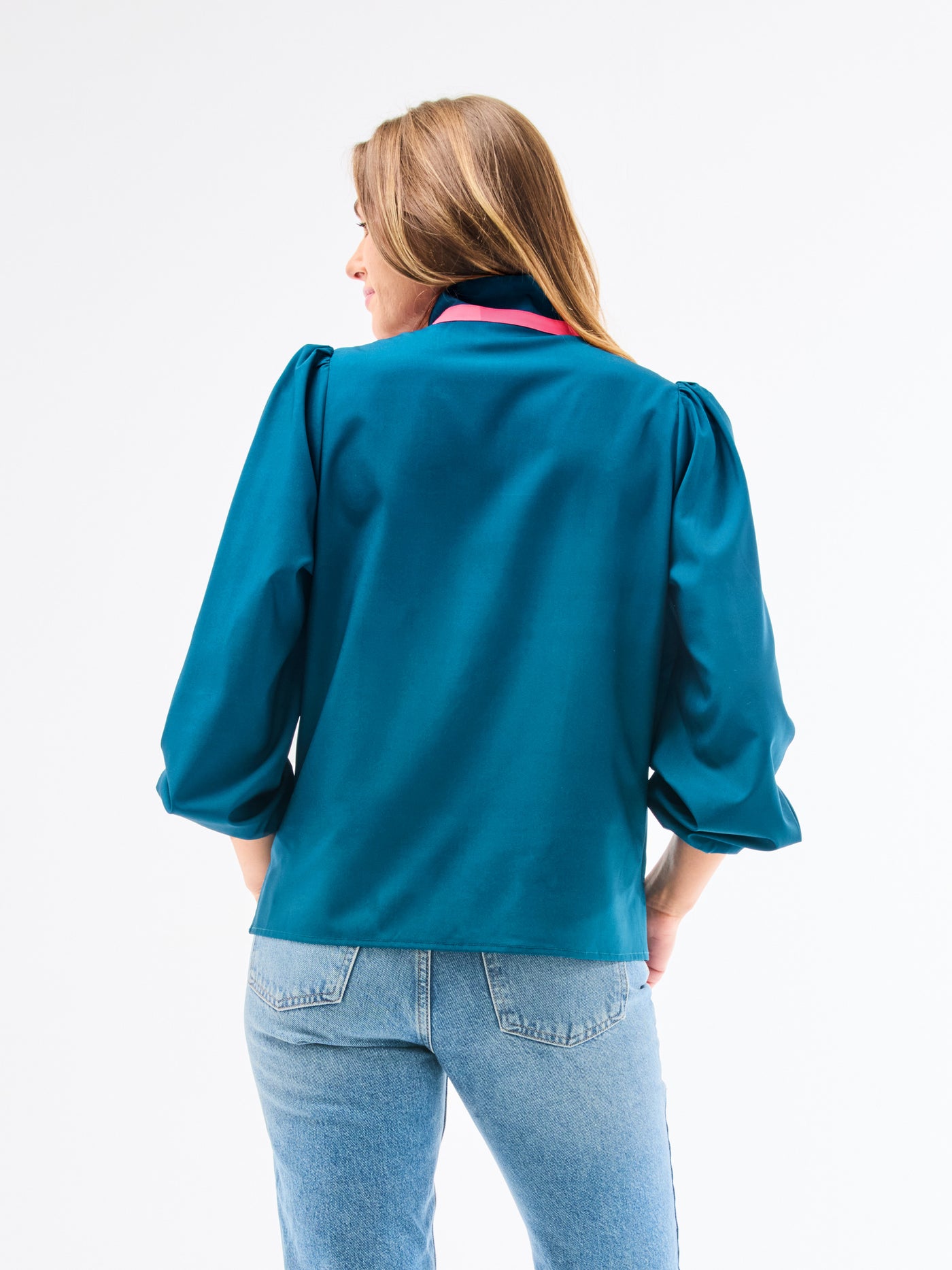 Person wearing a teal blouse and blue jeans on a white background