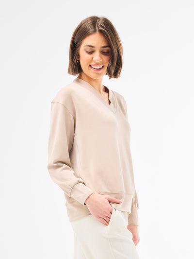 Woman wearing a beige sweatshirt against a white background