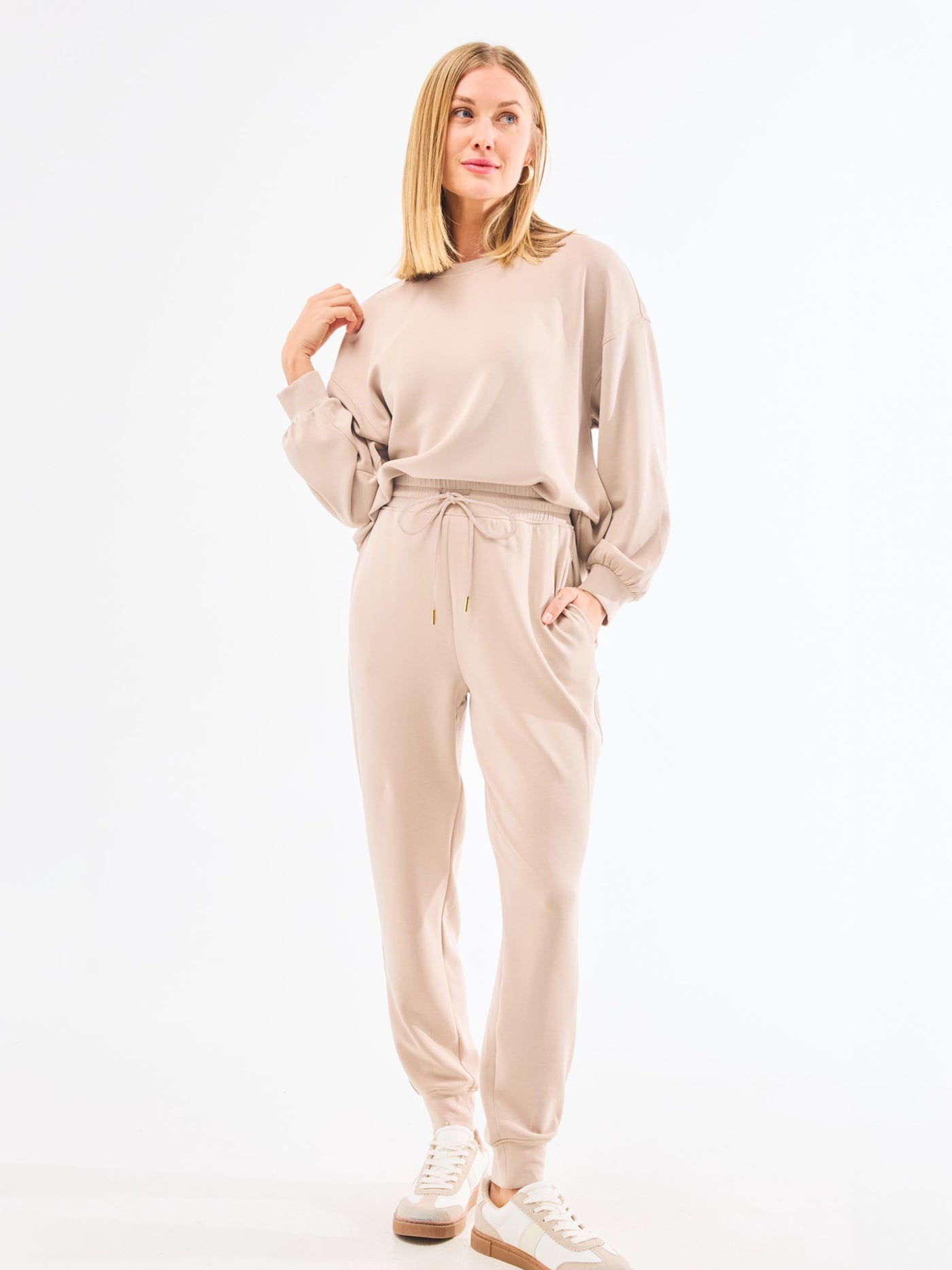 Woman wearing a beige tracksuit on a white background