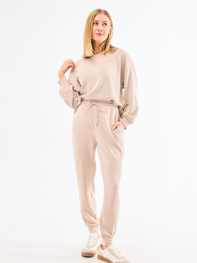 Woman wearing a beige tracksuit on a white background