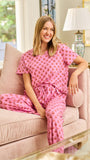 Woman in pink floral pajamas sitting on a couch in a well-lit room.
