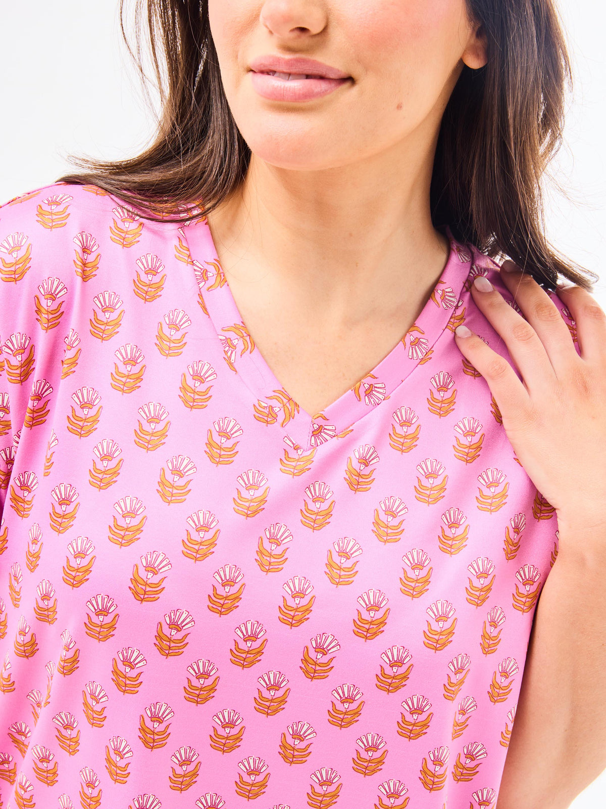 Close-up of a pink top with a subtle pattern worn by a person.