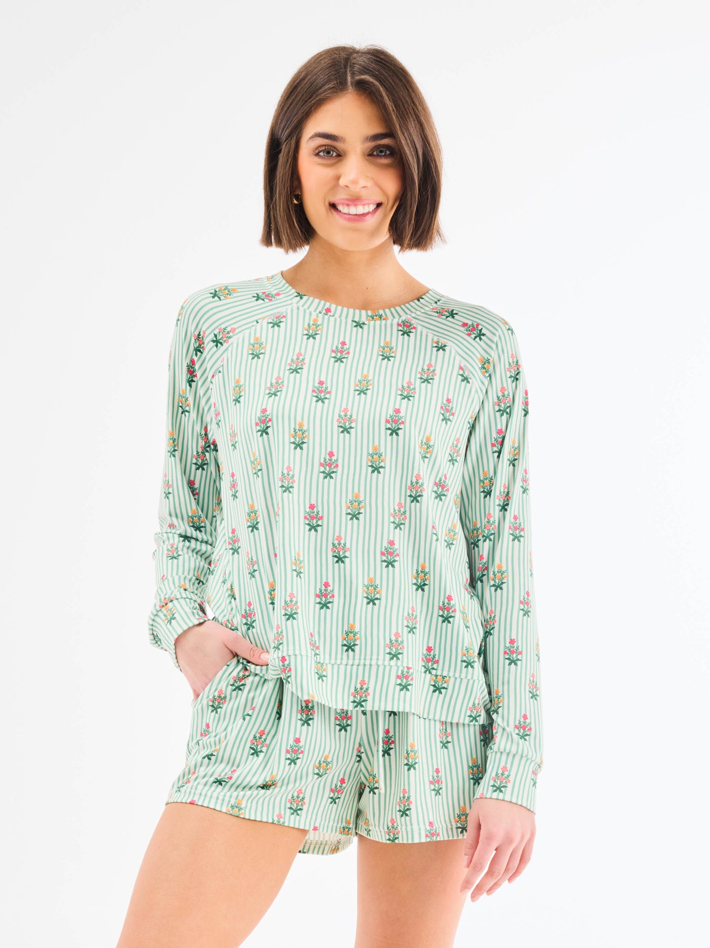 Woman wearing a green floral patterned romper on a white background