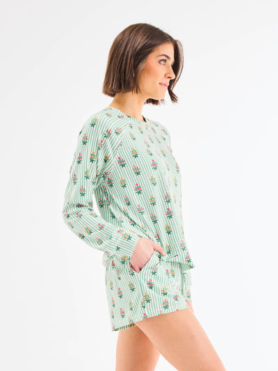 Woman wearing a green patterned pajama set on a white background