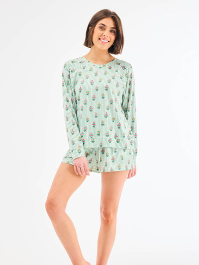 Woman wearing a green patterned pajama set on a white background