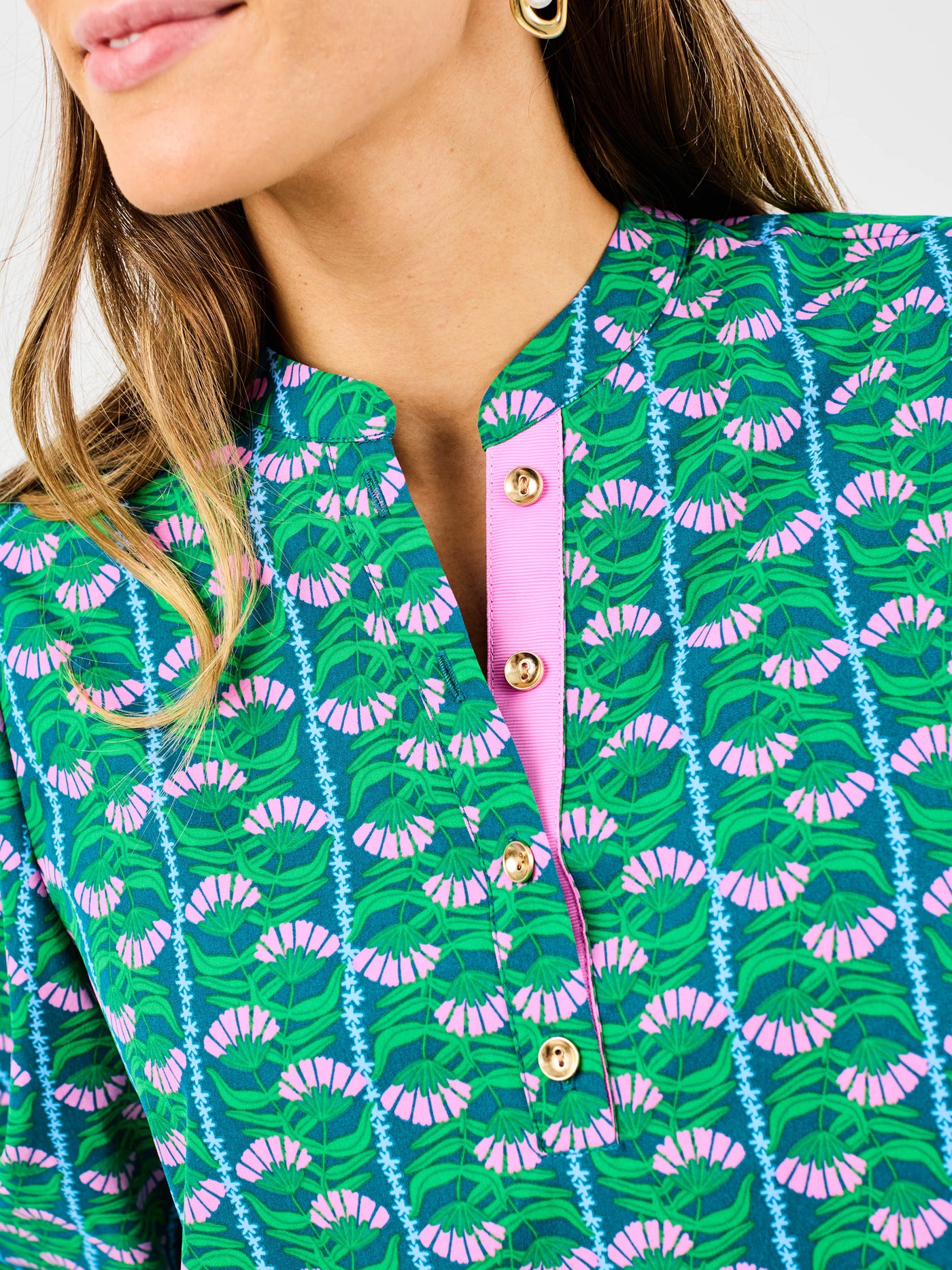 Close-up of a person wearing a green patterned shirt with pink accents.