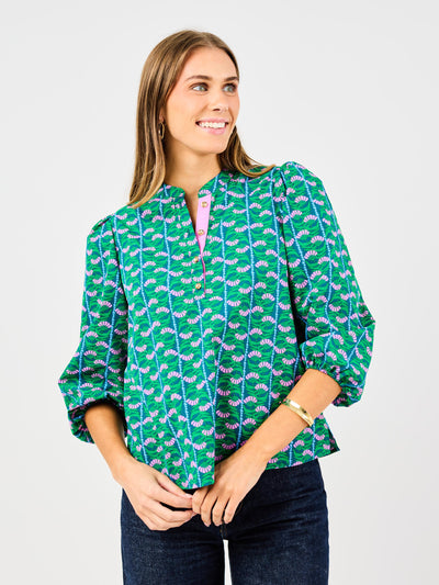 Woman wearing a green patterned blouse with a white background