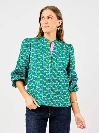 Woman wearing a green patterned blouse with a plain background
