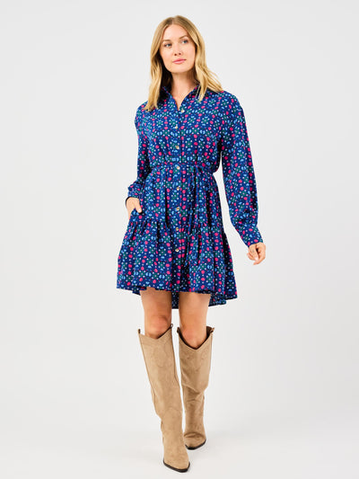 Woman wearing a blue floral dress with long sleeves and beige knee-high boots on a white background