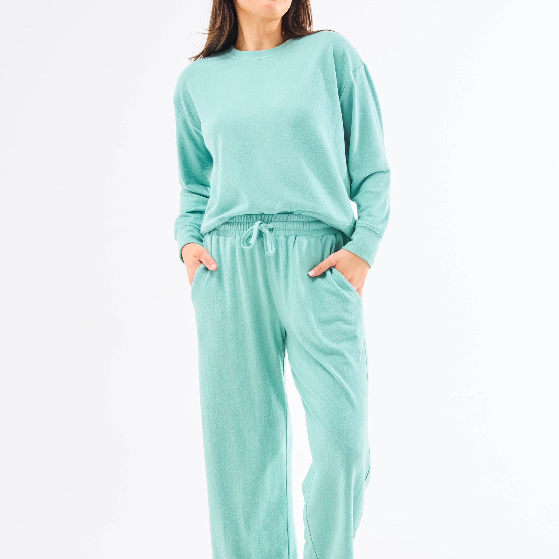 Woman wearing a teal loungewear set on a white background