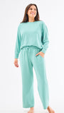 Woman wearing a mint green pajama set on a white background