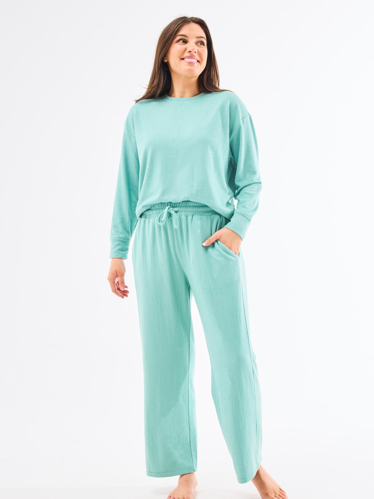 Woman wearing a mint green pajama set on a white background