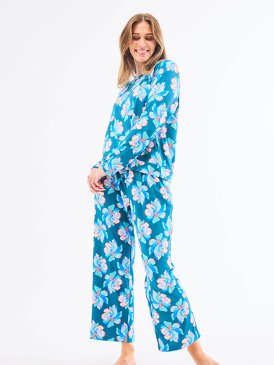 Woman wearing a blue/green floral pajama set on a white background