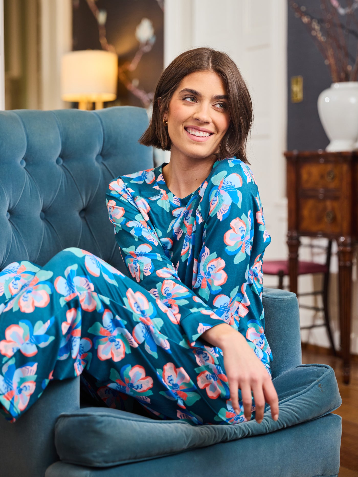Woman in a floral pajamas sitting on a blue chair in an indoor setting