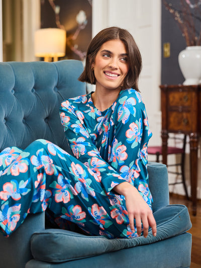 Woman in a floral pajamas sitting on a blue chair in an indoor setting