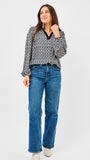 Woman wearing a patterned blouse and blue jeans on a white background