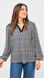 Woman wearing a patterned blouse and jeans on a plain background