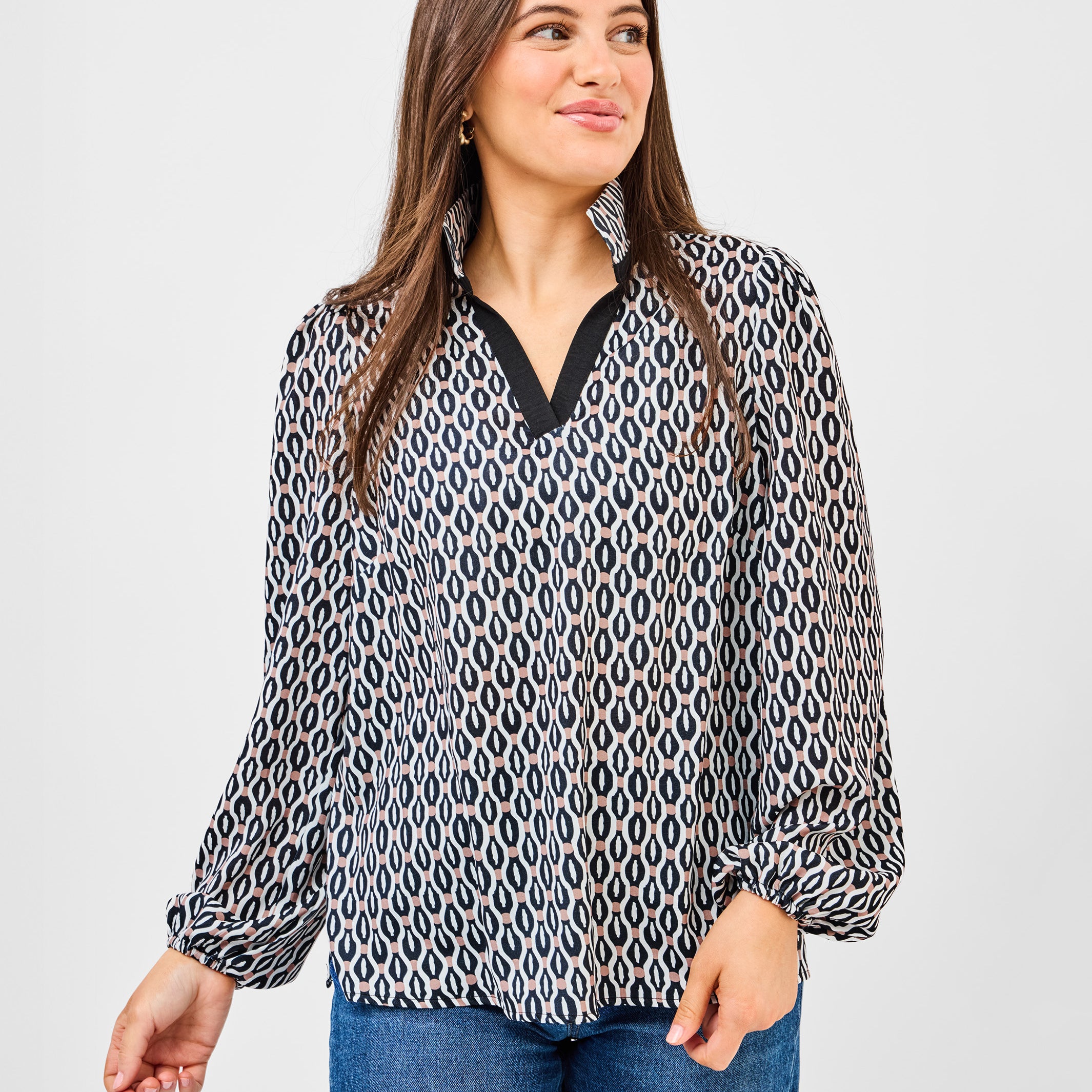 Woman wearing a patterned blouse and jeans on a plain background