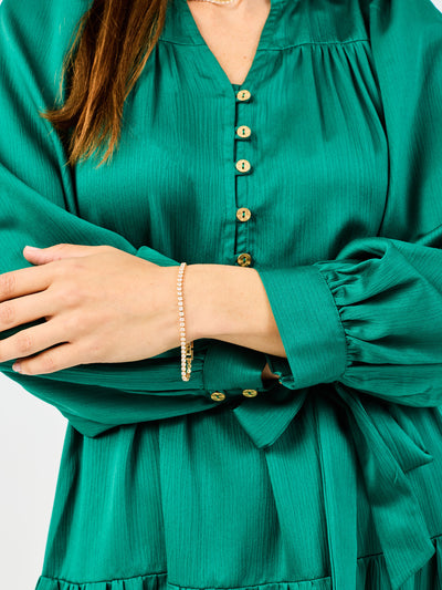 Green dress with gold buttons worn by a person, on a white background