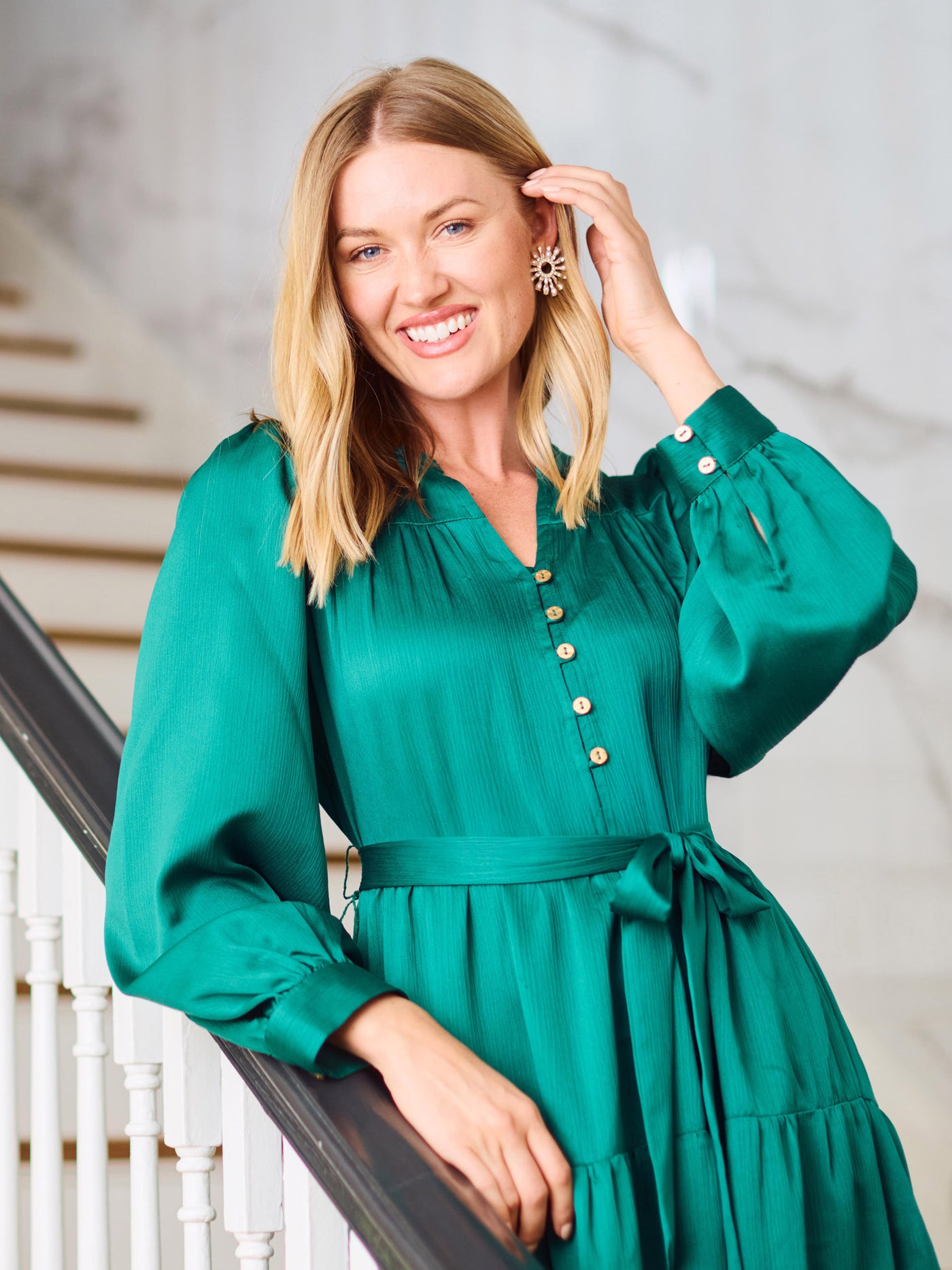 Woman in a green dress standing indoors with a neutral background