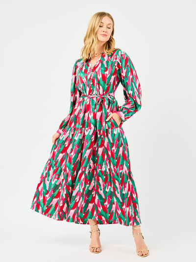 Woman wearing a colorful patterned holiday dress with pinks, greens, reds and whites on a white background